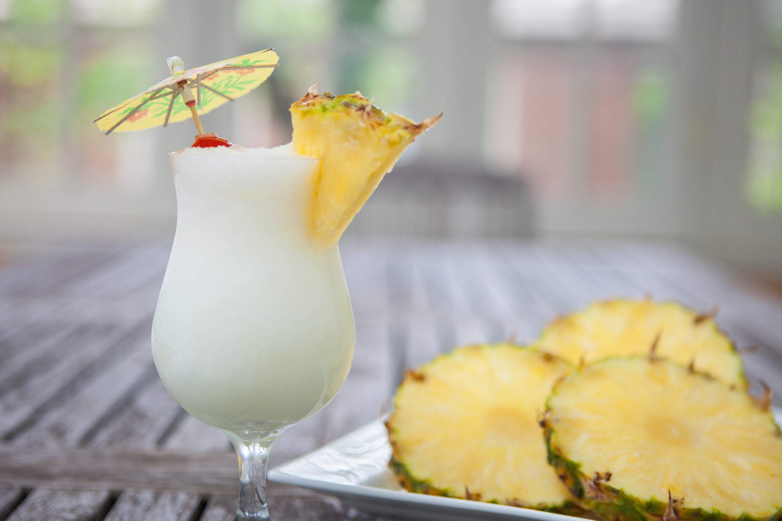 Pina colada with pineapple slices on wooden table Pina Colada and Pineapple on a plate on a wooden table.